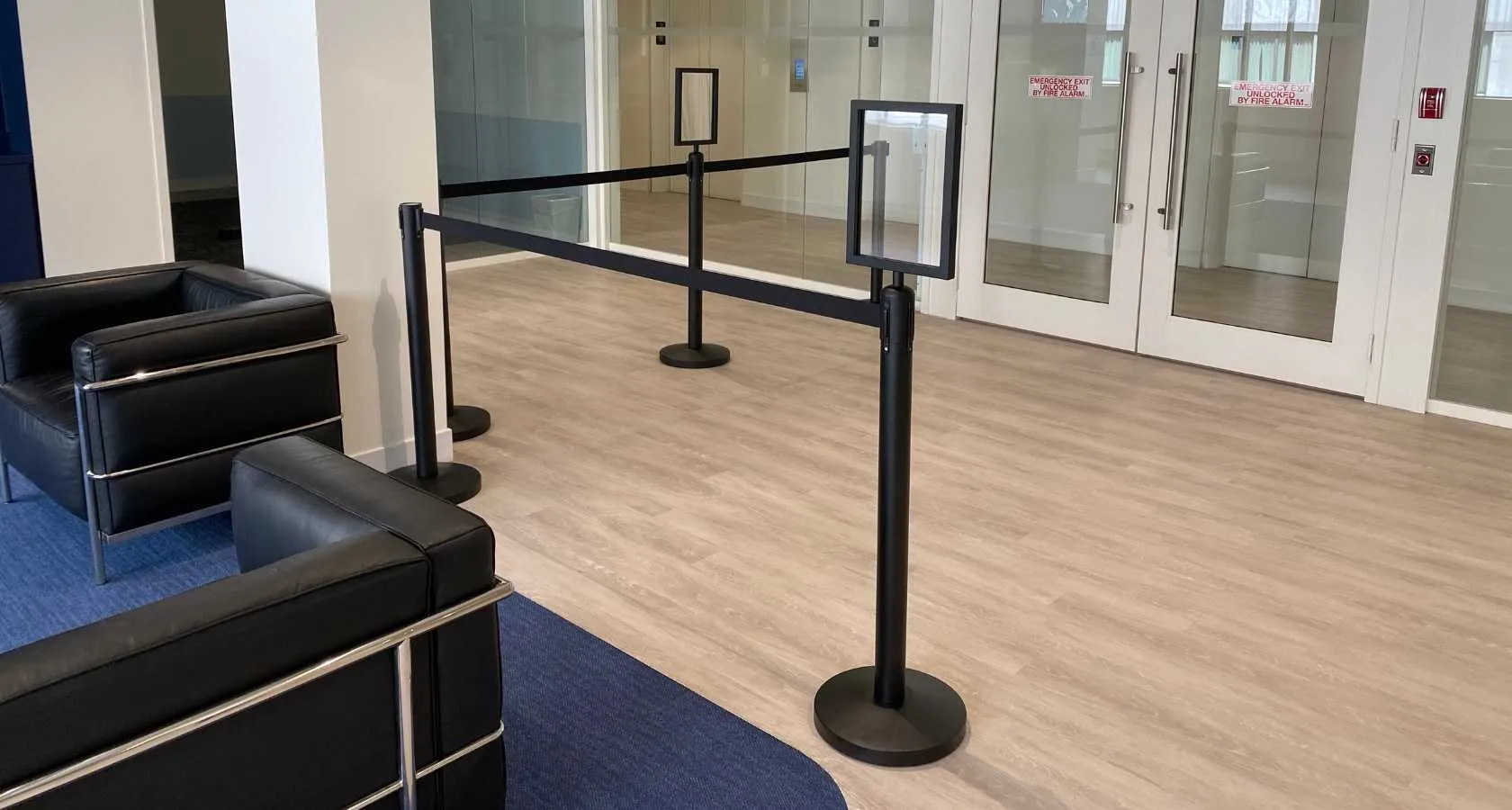 A topper sign mounted above a stanchion post at an entrance