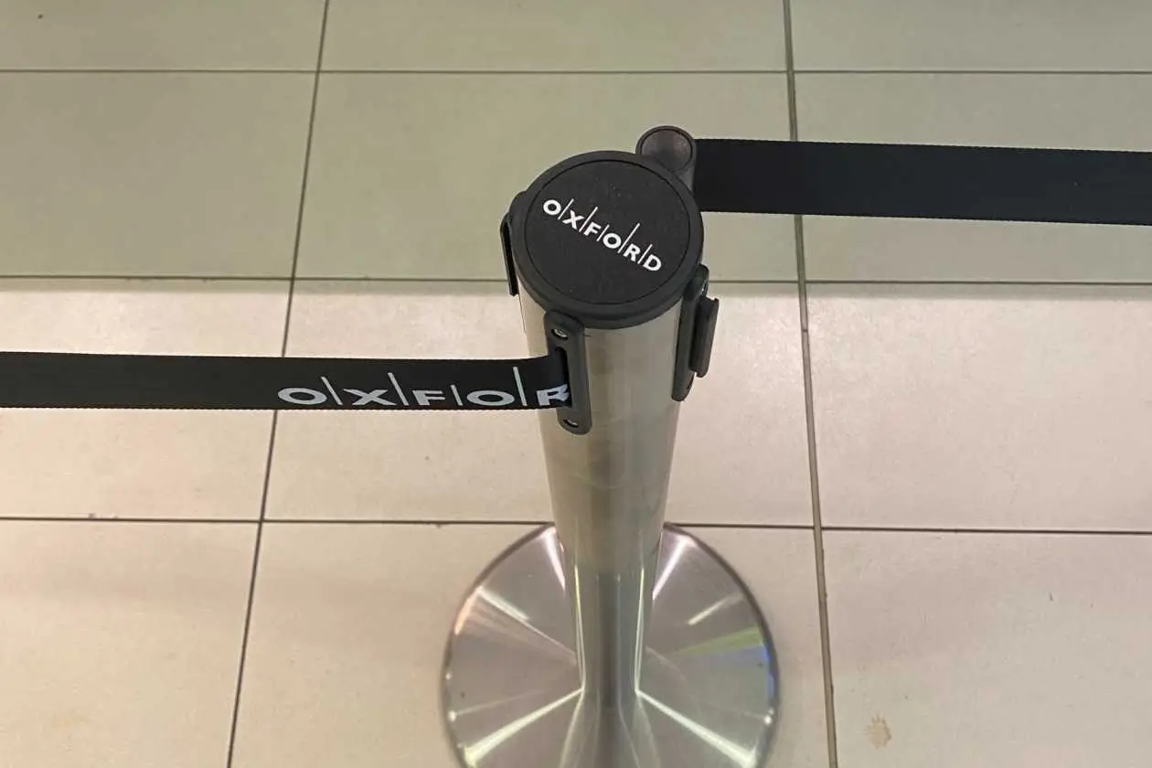 A printed belt clipped to a chrome post head on a tiled floor