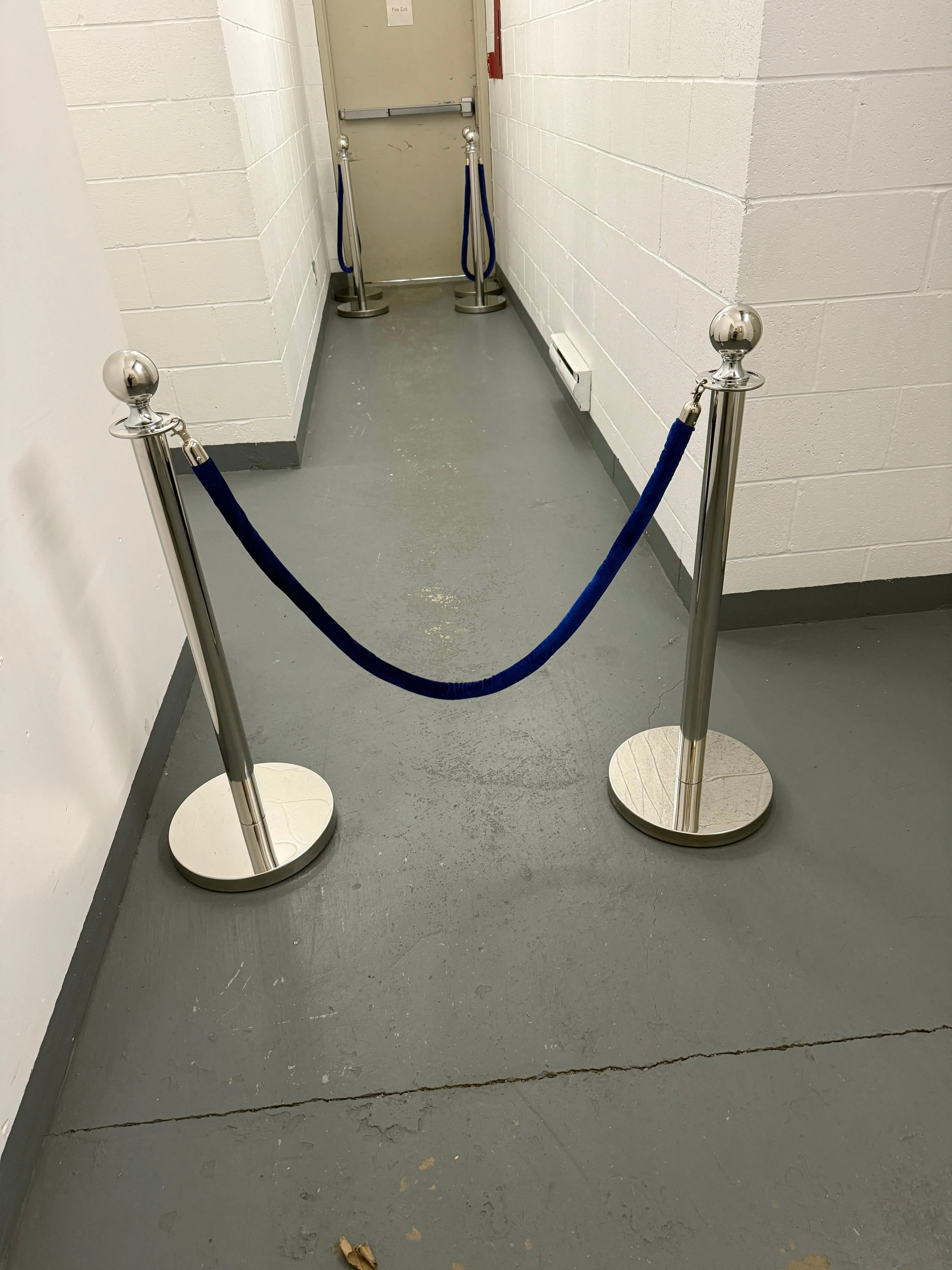 Silver rope stanchion posts joined by a navy velvet rope across a corridor