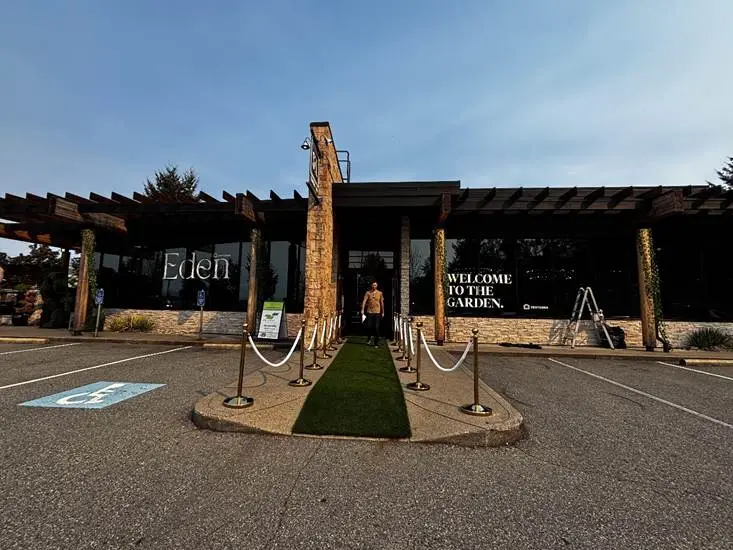 Rope stanchion posts marking an outdoor entrance along a turf walkway at dusk