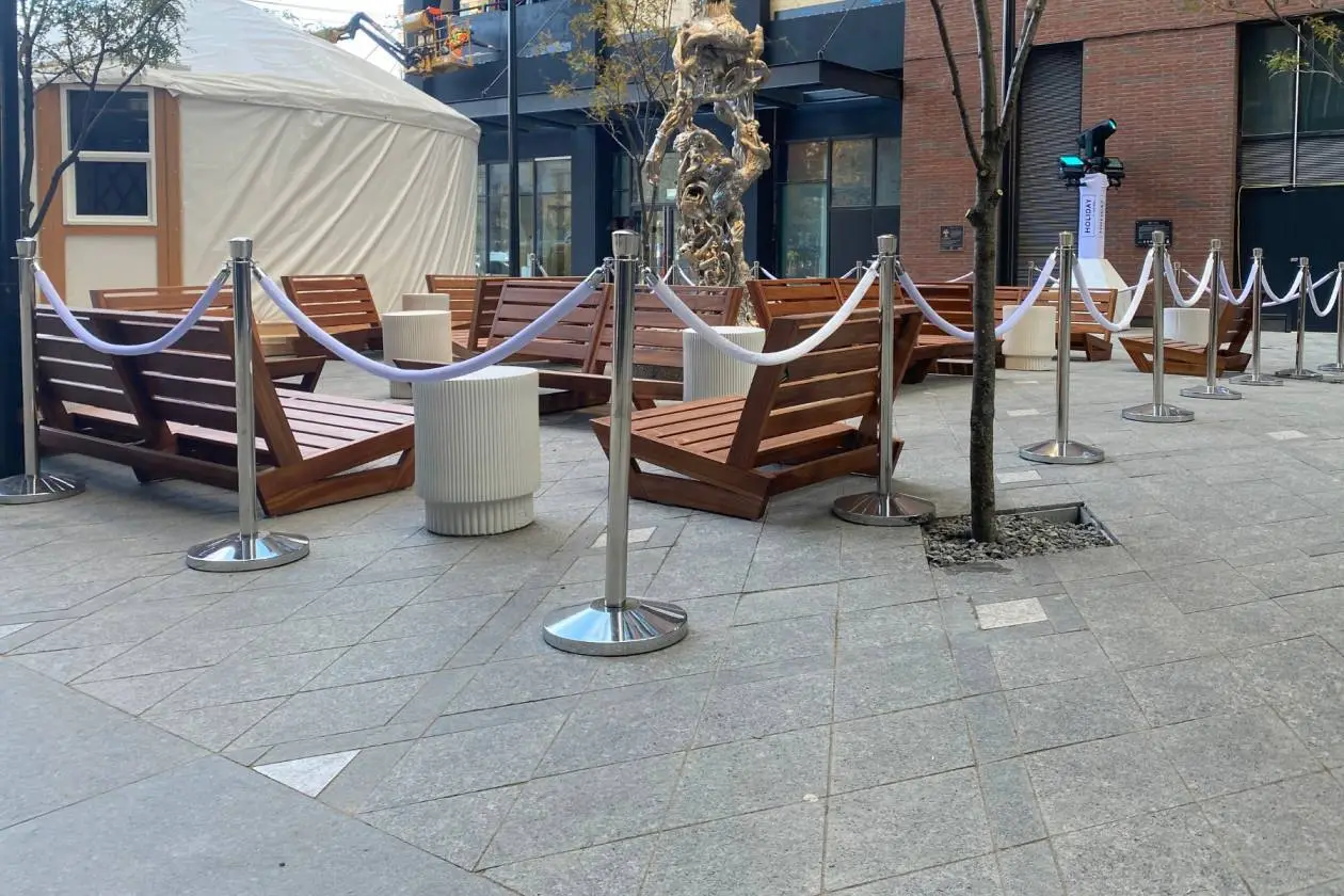 White velvet ropes on chrome posts marking a route across a plaza