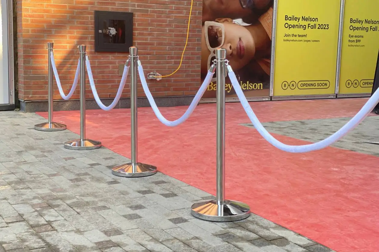 White velvet ropes on chrome posts beside a red carpet at a shopfront